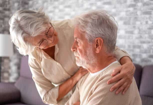 Elderly woman comforting her husband at home, symbolizing emotional support during the 7 stages of Alzheimer's chart.