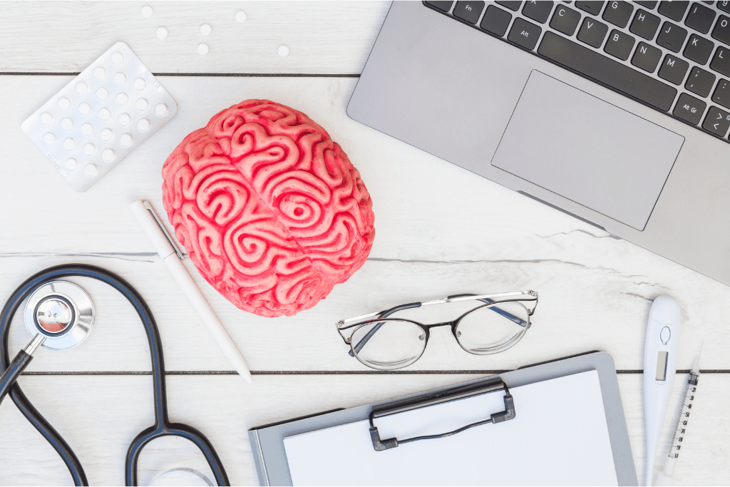 Medical tools and a model brain on a desk representing neurological assessment related to how quickly does small vessel disease progress.
